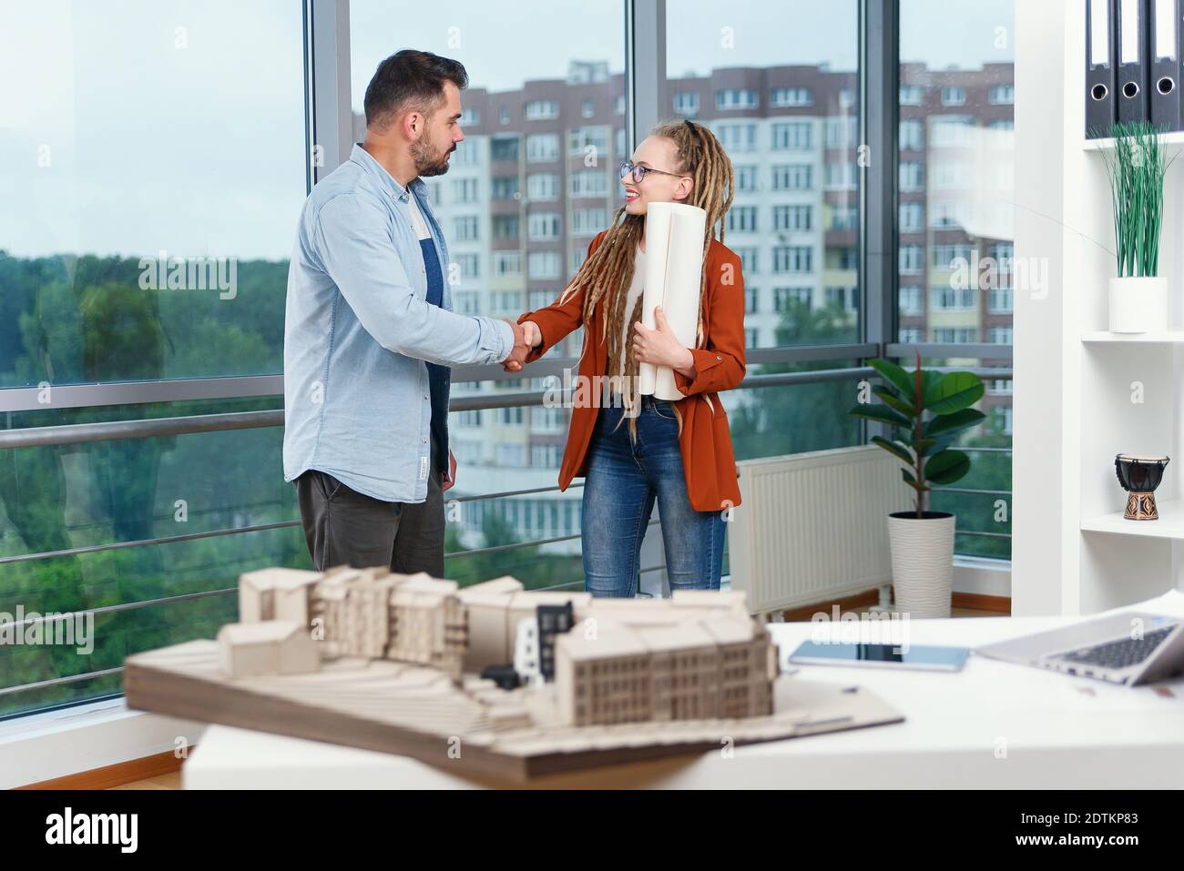 Piacevole esperienza moderna elegante e soddisfatto giovani designer discutere momenti di lavoro utilizzo di un progetto con progetto di nuovi edifici vicino a panoramic win Foto Stock