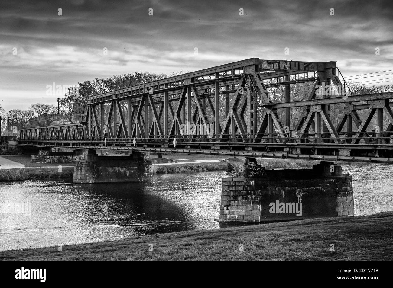 Una scala di grigi di un vecchio ponte sul fiume su una nuvolosa Foto Stock