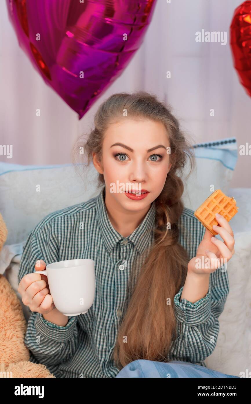 Sorpresa giovane donna con capelli lunghi ha la prima colazione a letto il giorno di San Valentino. Foto di alta qualità Foto Stock