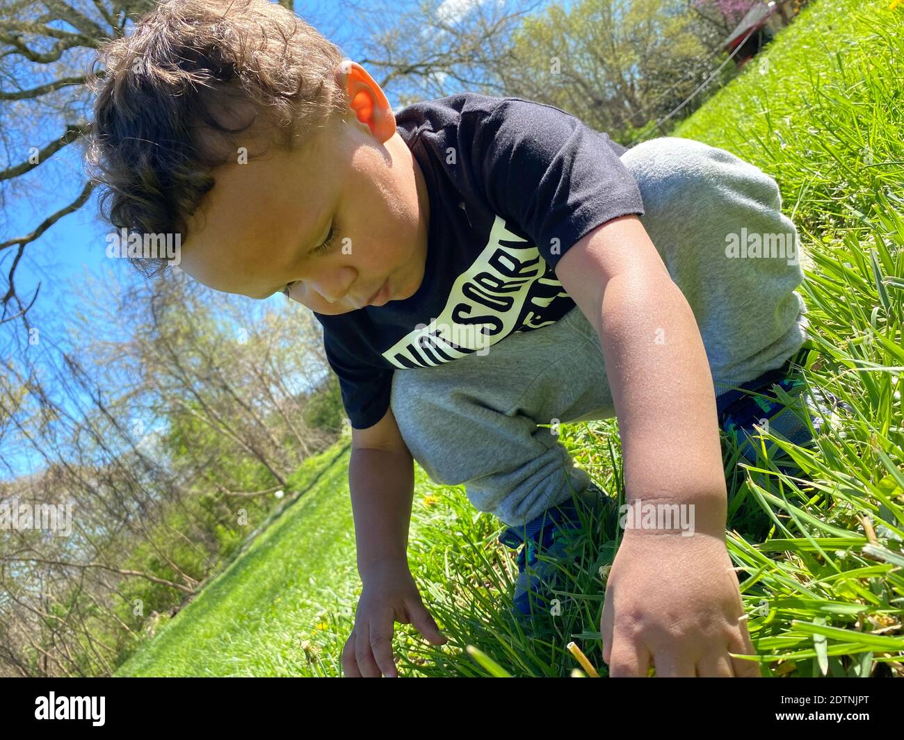 Lunghezza completa del bambino che accovacciano sulla terra erbosa nel  parco Foto stock - Alamy