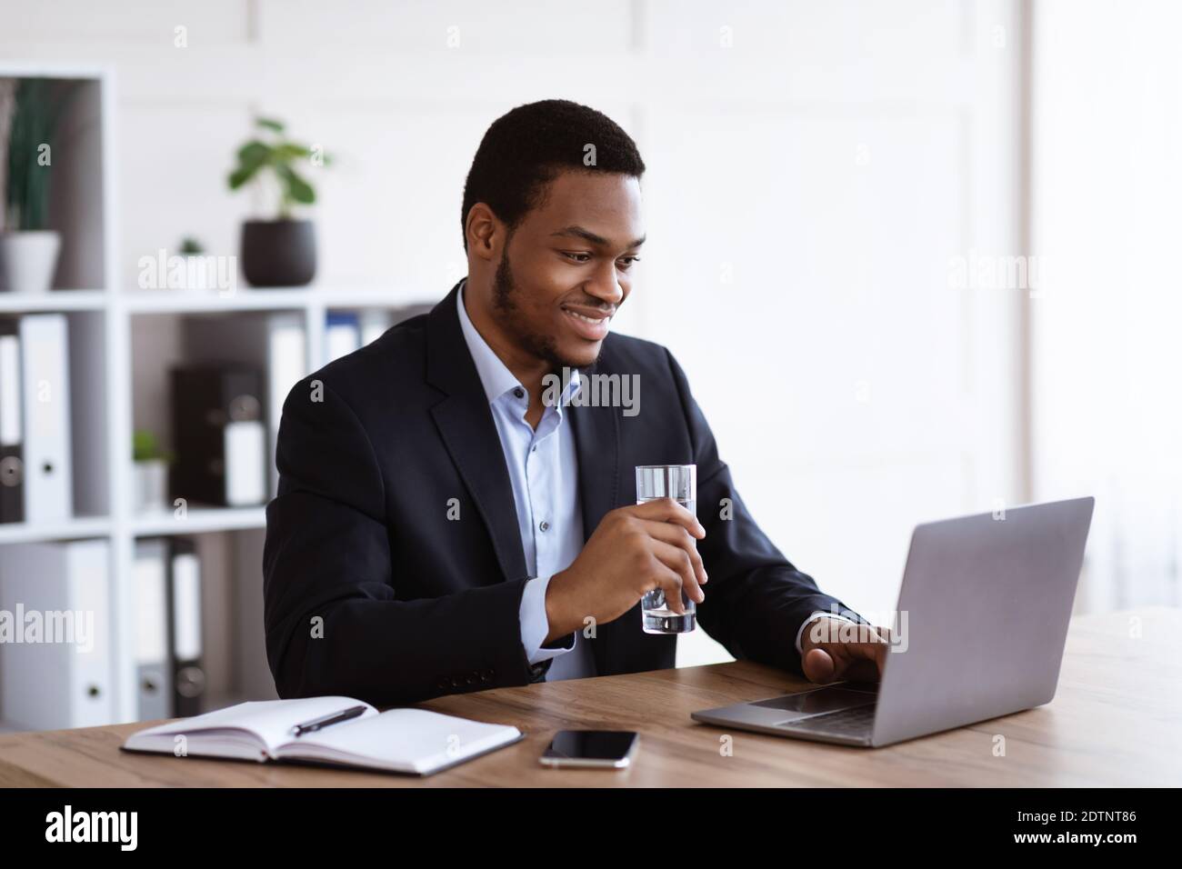 Sorridente manager nero che legge il rapporto sulle vendite sul notebook Foto Stock