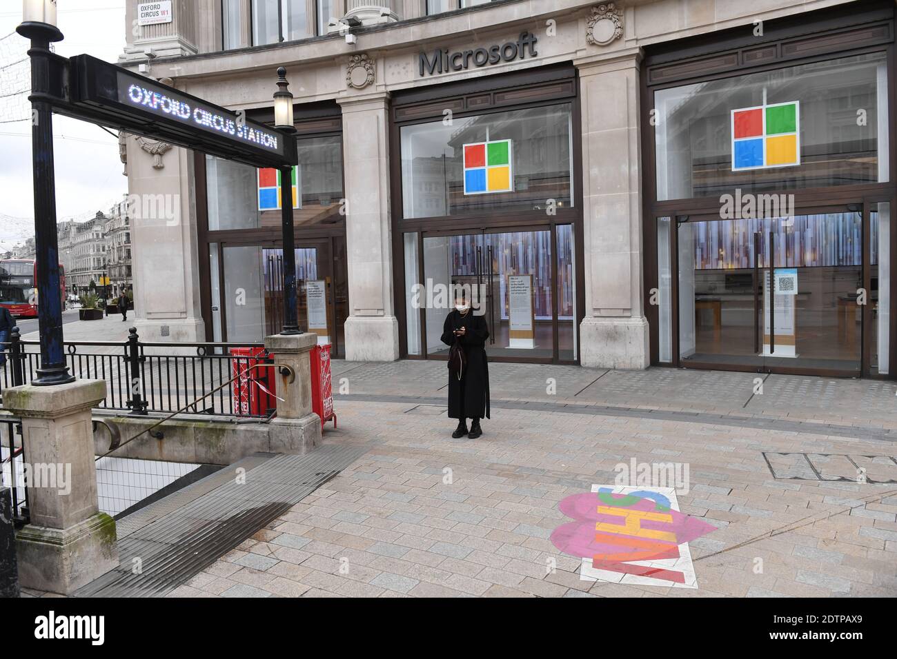 Una donna si trova al di fuori del negozio Microsoft chiuso alla stazione della metropolitana di Oxford Circus, nel centro di Londra, dove le persone sono state informate contro tutti i viaggi, ma essenziali, dopo che la capitale è stata spostata nel livello 4 delle restrizioni del coronavirus. Foto Stock
