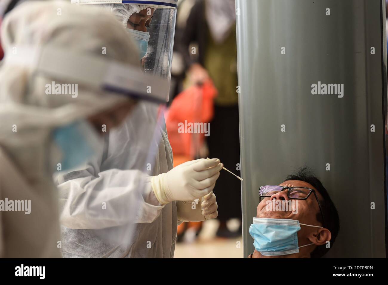 Giacarta, Indonesia. 22 dicembre 2020. Un operatore sanitario prende un campione di tampone nasale di un passeggero del treno per testare la COVID-19 alla stazione ferroviaria di Pasar Senen a Giacarta, Indonesia, il 22 dicembre 2020. I casi COVID-19 in Indonesia sono saliti di 6,347 nelle ultime 24 ore a 678,125, con il numero di morti che si aggiunge da 172 a 20,257, ha detto il Ministero della Salute Martedì. Credit: Agung Kuncahya B./Xinhua/Alamy Live News Foto Stock