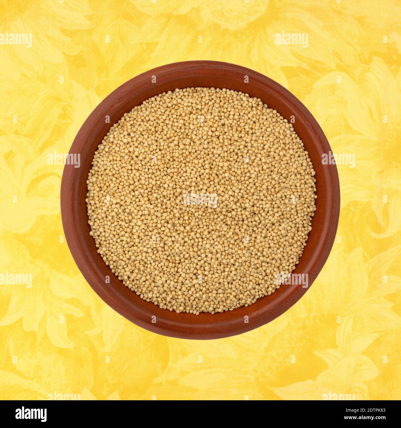 Vista dall'alto dei semi di amaranto in una piccola ciotola su sfondo floreale giallo. Foto Stock