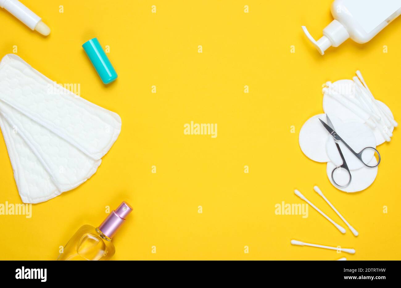 Copy space prodotti per la bellezza e l'igiene delle donne su sfondo giallo pastello. Flacone di profumo, rossetto igienico, tamponi, crema per bottiglie, forbici per unghie. Piatto Foto Stock