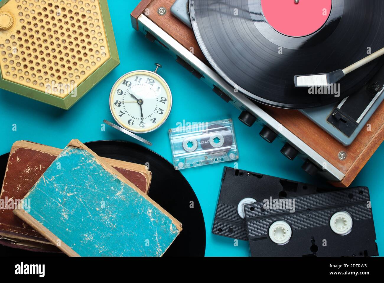 Attributi di stile retrò a disposizione piatta, supporti 80s. Lettore di vinile, videocassette, audiocassette, dischi, radio, sveglia d'epoca, vecchi libri su Blue bac Foto Stock
