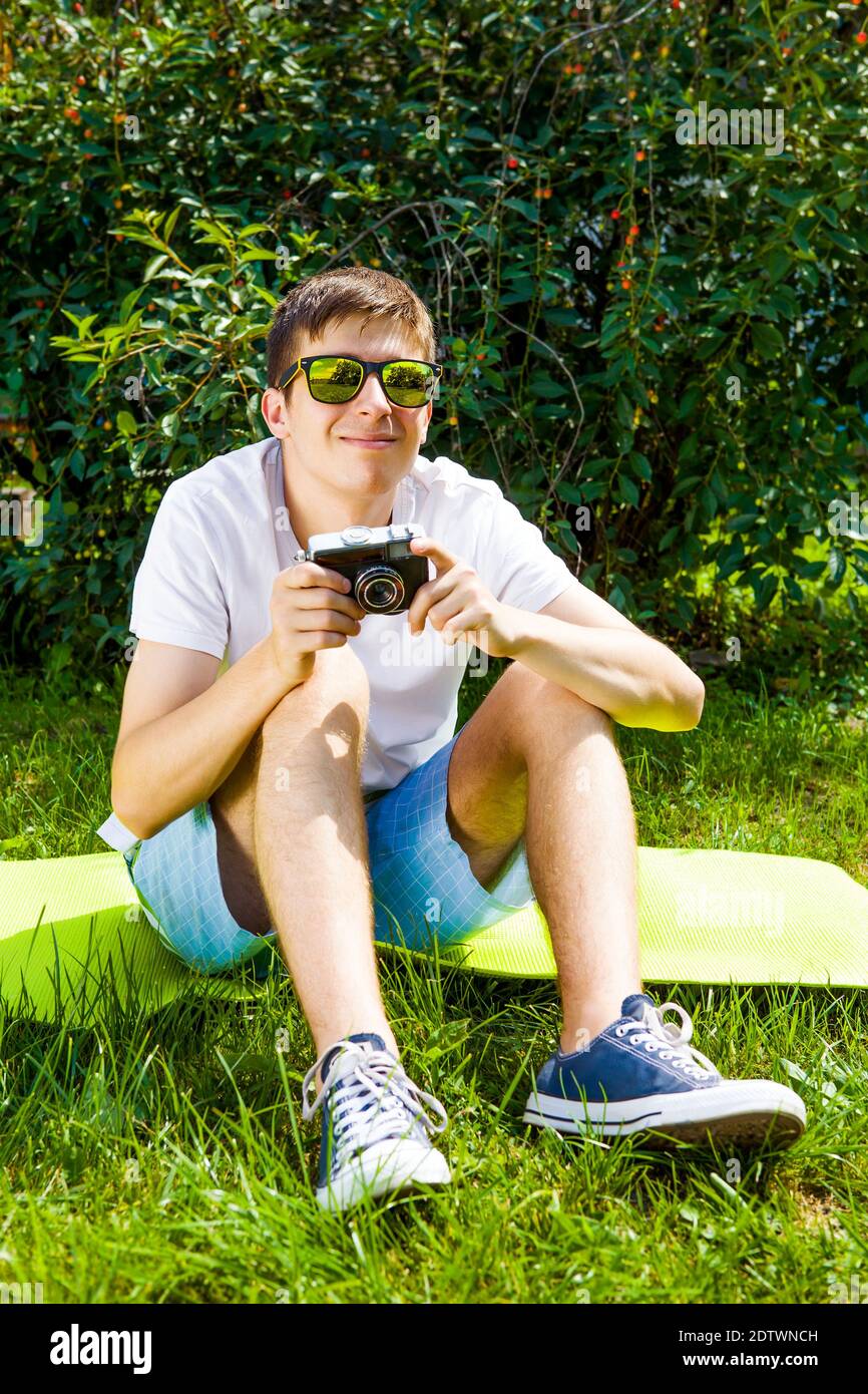Giovane uomo con una macchina fotografica d'epoca sul prato all'aperto Foto Stock