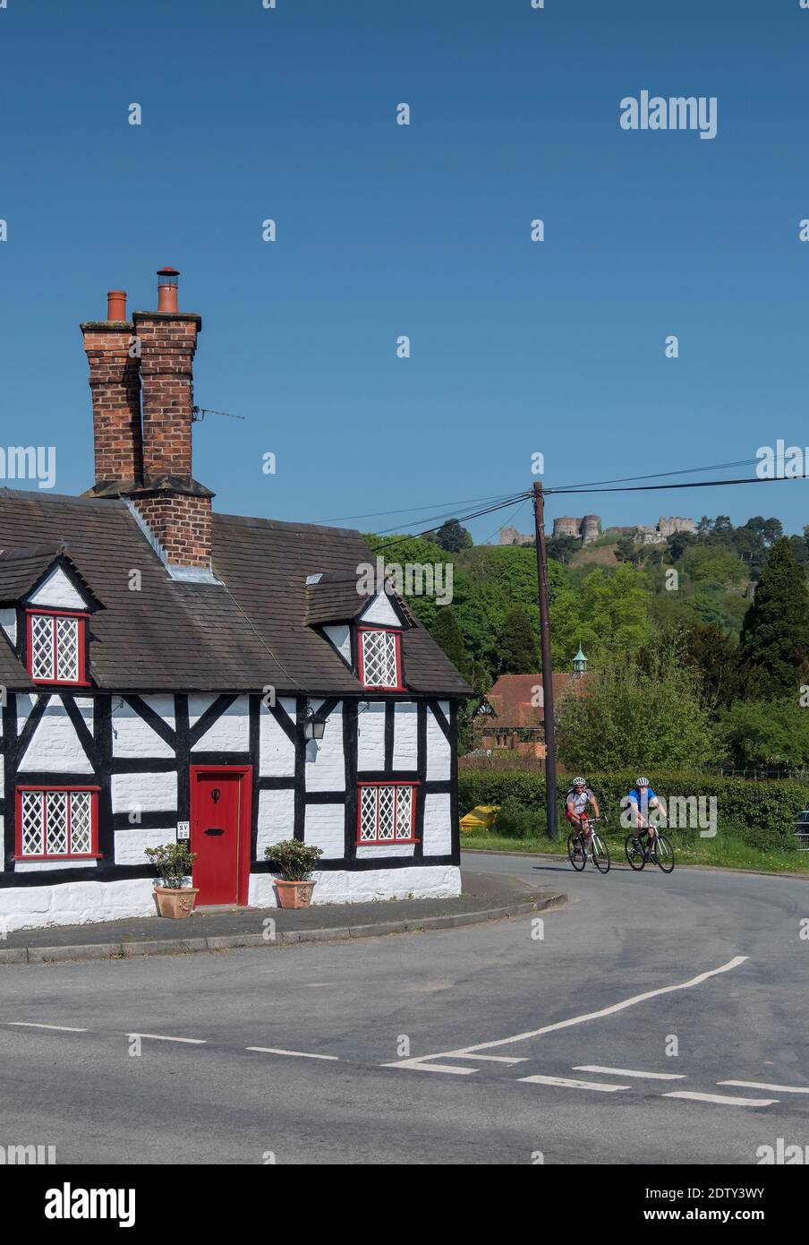 I ciclisti passano da Smithy Cottage & Beeston Castle, Beeston, Cheshire, Inghilterra, Regno Unito Foto Stock