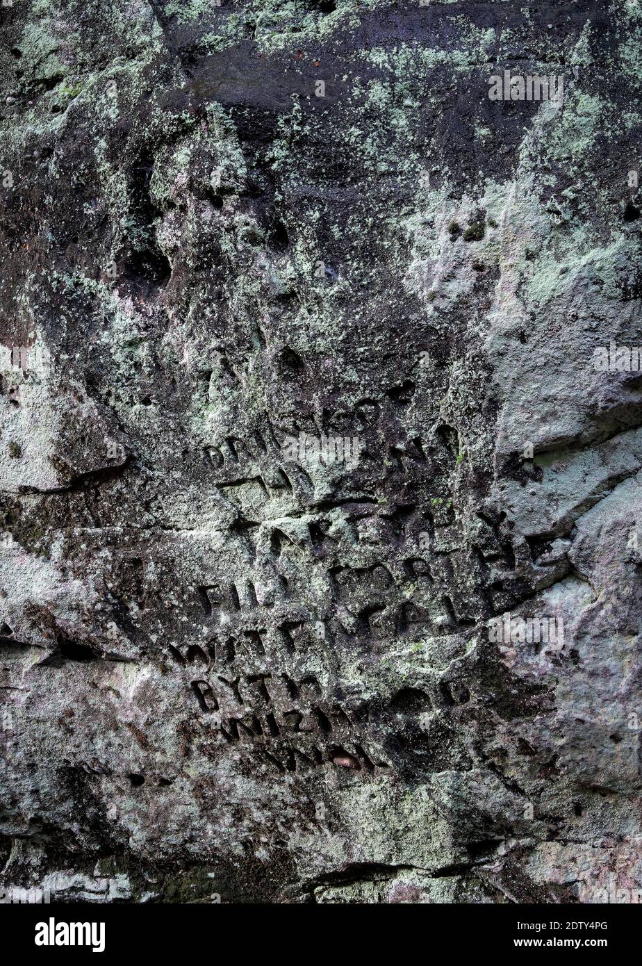 Iscrizione e faccia scolpita nel Wizards Well Boulder, Alderley Edge, Cheshire, Inghilterra, Regno Unito Foto Stock