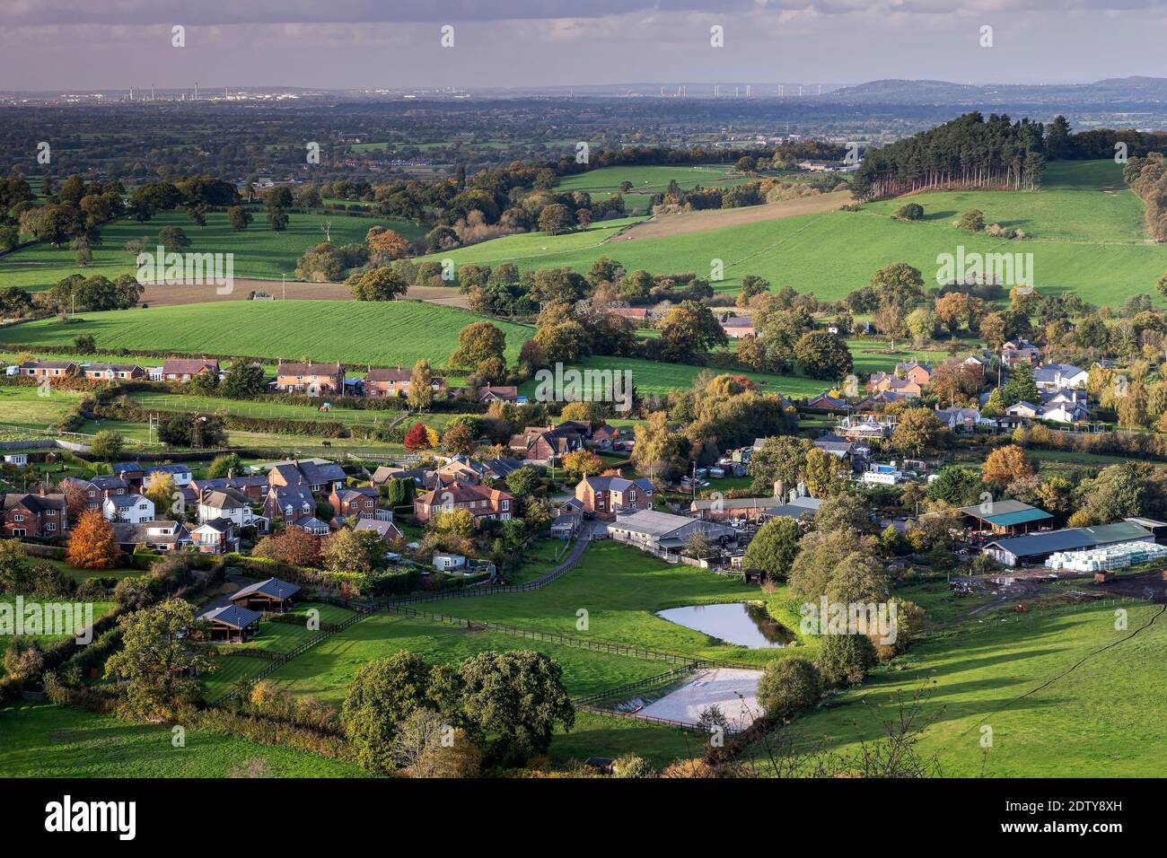 Villaggio di Brown Knowl, Cheshire Plain e Distant Stanlow Oil Refinery, da Bickerton Hill, Cheshire, Inghilterra, Regno Unito Foto Stock