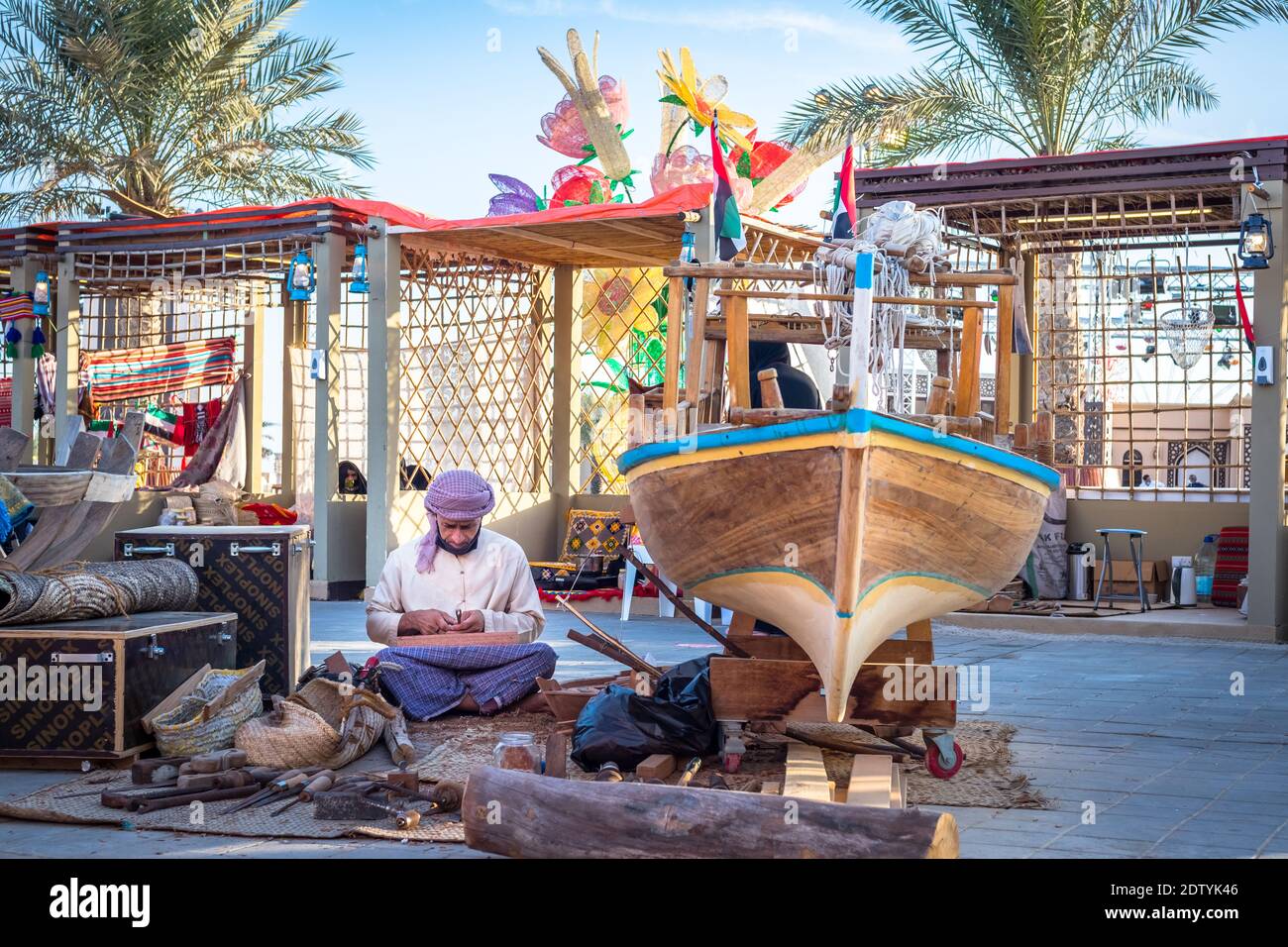 Pescatore arabo, riparando la rete di pesca fatta in casa e yacht di legno, indossando la maschera facciale e si siede sul pavimento del tradizionale boam Foto Stock