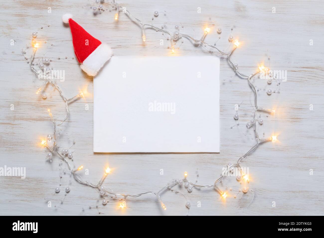 Biglietto d'auguri su sfondo in legno d'epoca con cappello Babbo Natale e  luplanti luci dei ghirlari. Biglietto d'auguri vuoto con luci di Natale.  Natale minimo Foto stock - Alamy