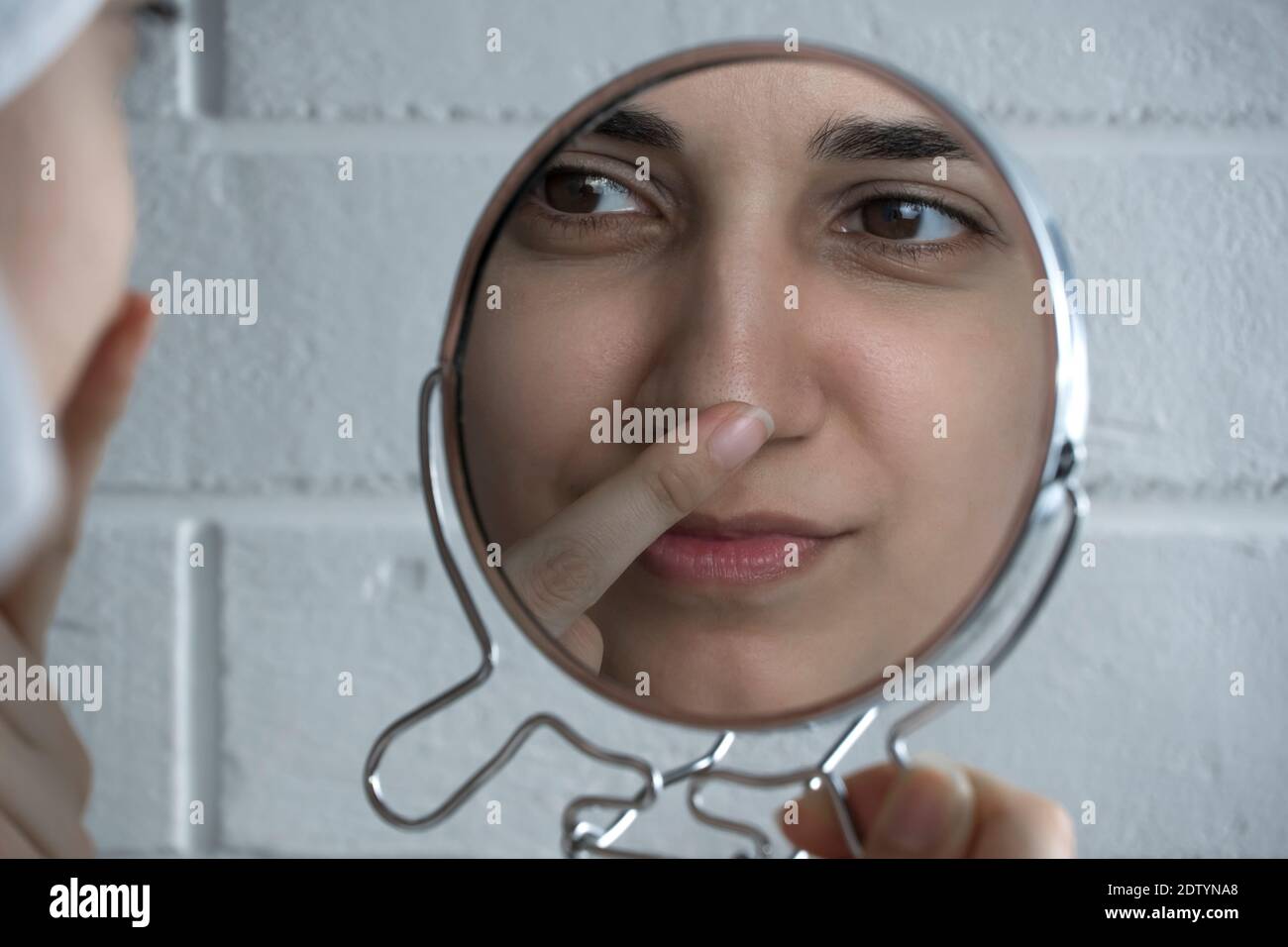 Puntini neri sul naso. Una giovane donna guarda il viso nello specchio. Cura della pelle, problema della pelle, pulizia. Bellezza naturale, naturalezza. Ragazza senza m. Foto Stock