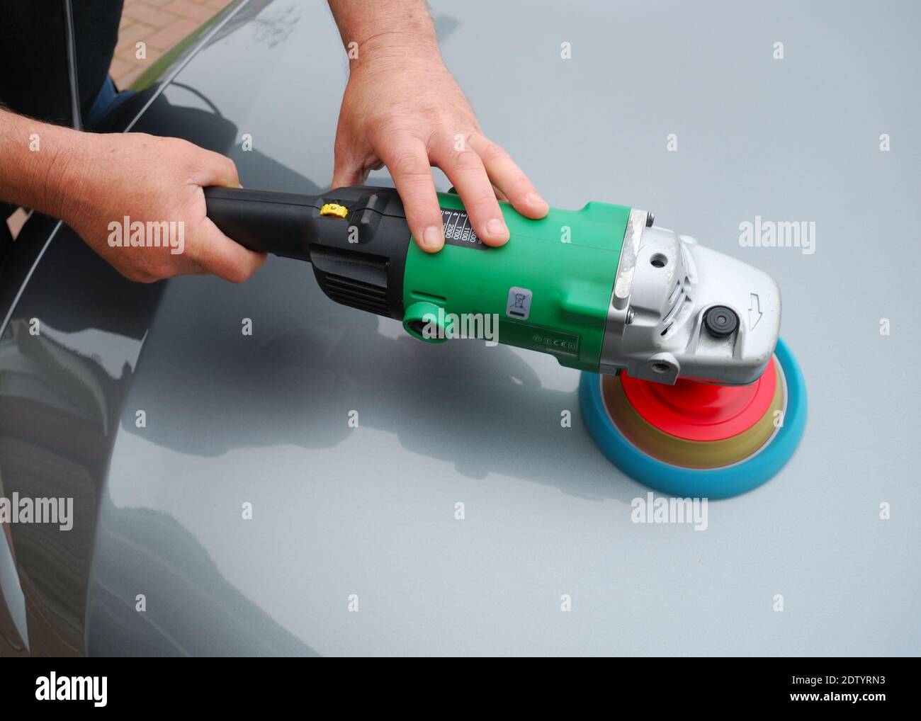 Un uomo che lucidano la superficie della vernice dell'automobile con la macchina lucidante e le imbottiture di schiuma per aumentare la lucentezza. Foto Stock