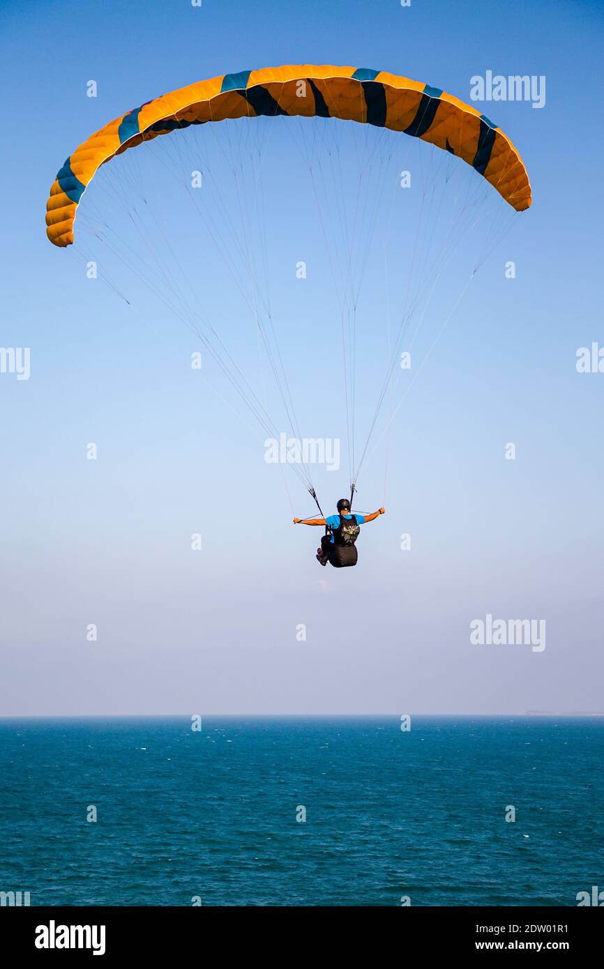 Parapendio che sorvola la costa del mare su sfondo blu cielo Foto Stock