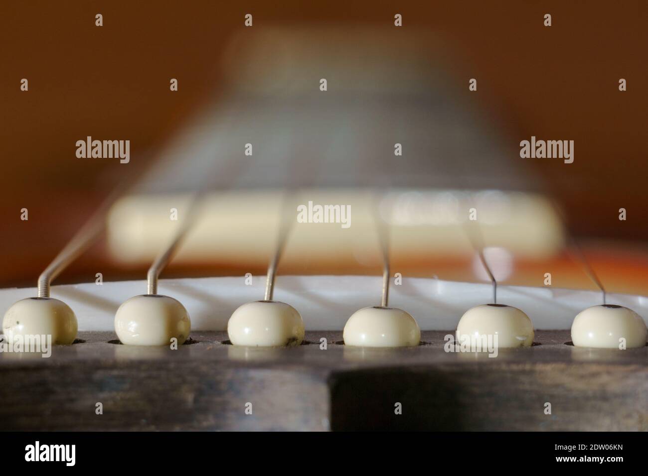 Dettaglio di un ponte di chitarra con sei spinotti e corde Foto Stock