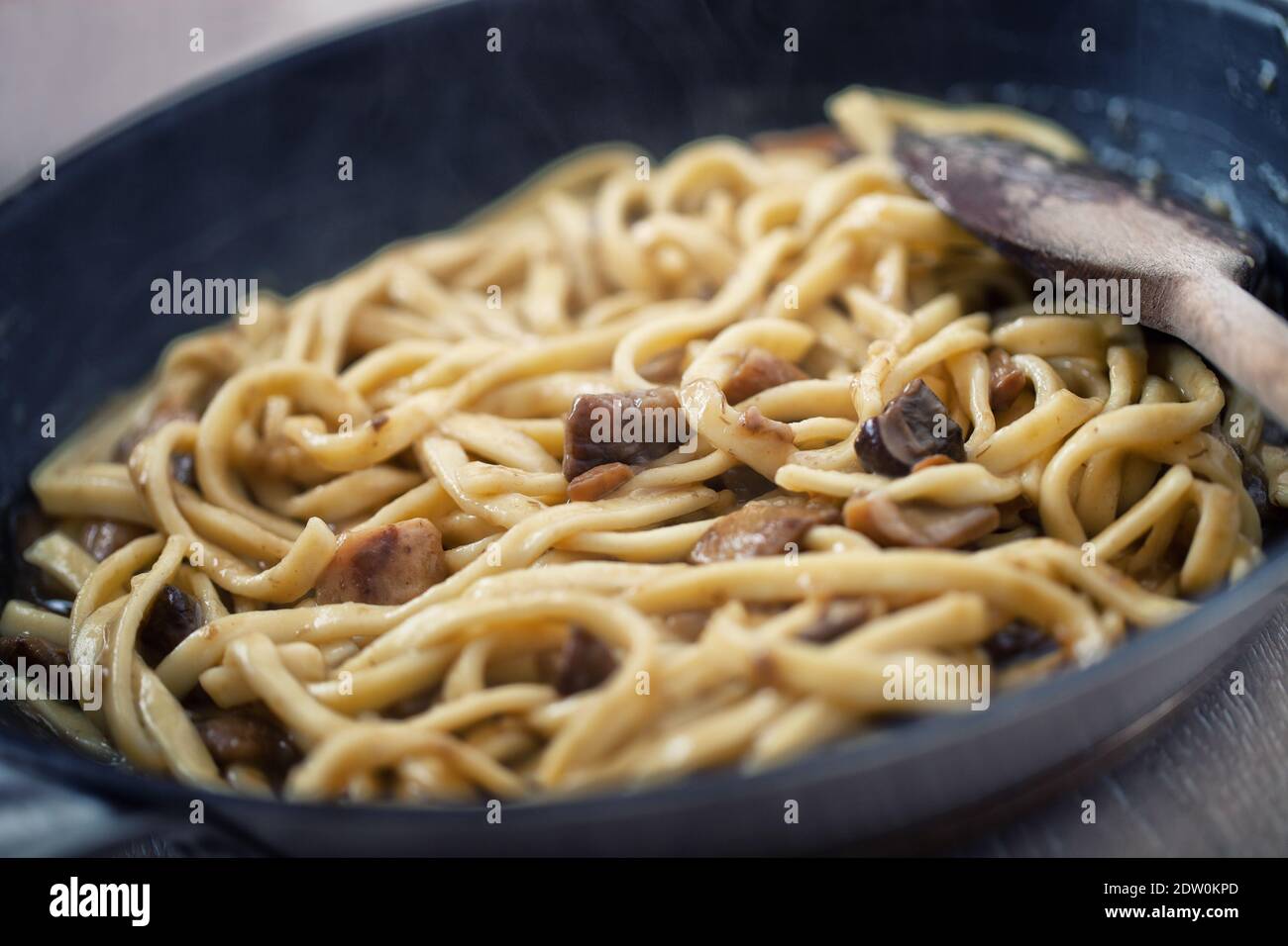 Cottura di tagliatelle fresche con funghi in una padella. Foto Stock