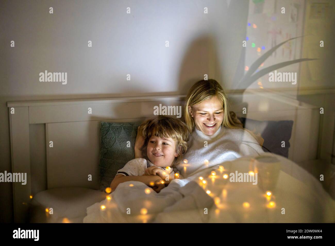 Madre e figlio che utilizzano il tablet digitale insieme di notte letto Foto Stock