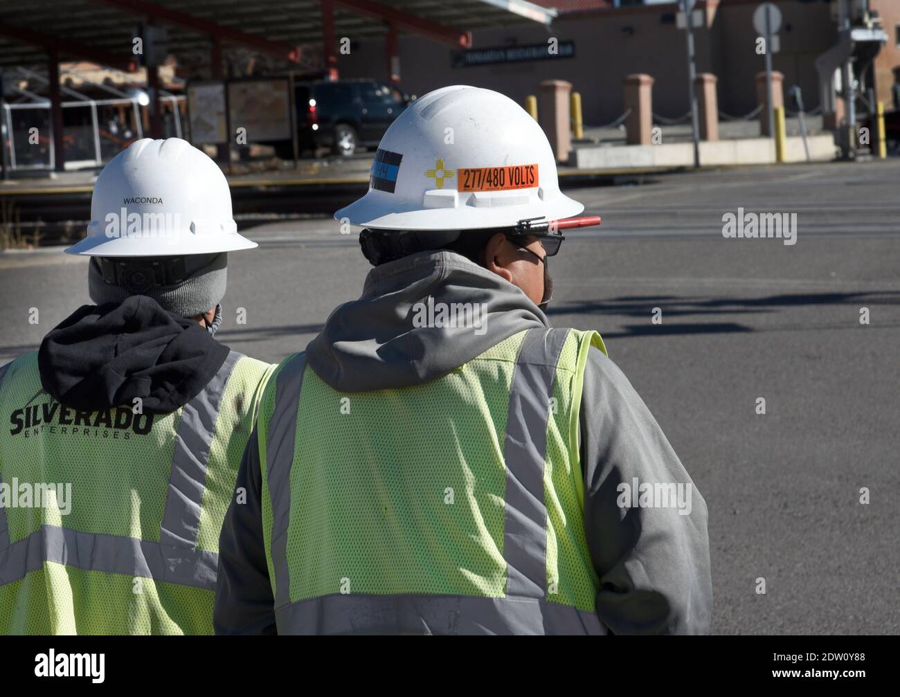 Due operai elettrici che indossano caschi di sicurezza completi del brim camminano per funzionare a Santa Fe, New Mexico. Foto Stock