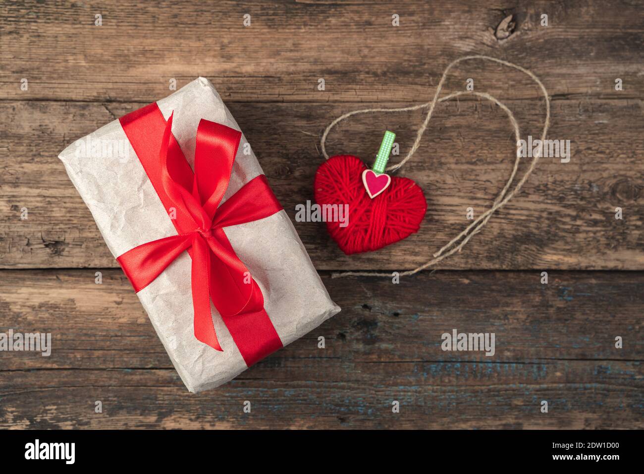 Cuore rosso e scatola regalo su sfondo di legno. Vista dall'alto, con spazio per la copia. Foto Stock