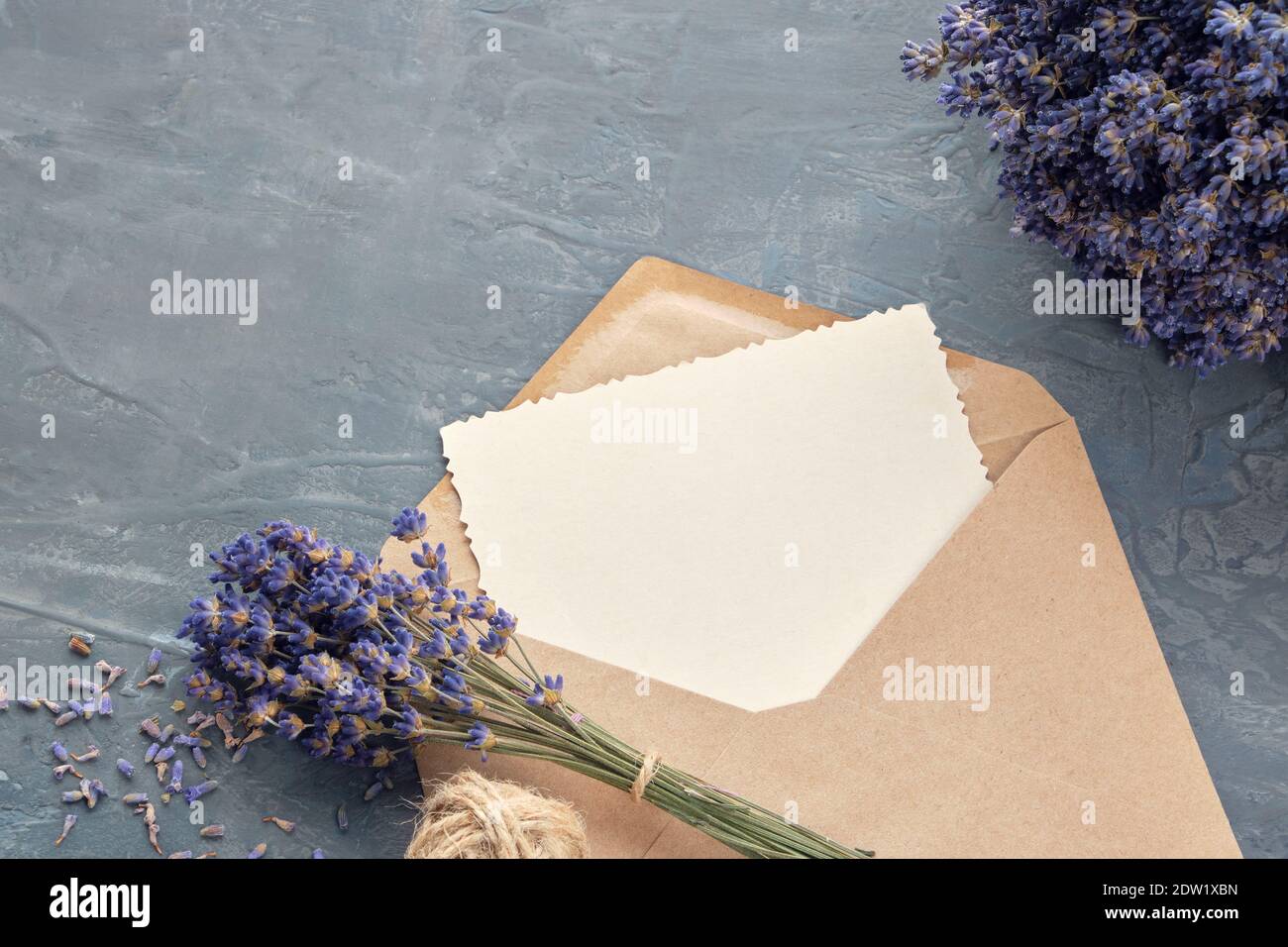 Biglietto d'auguri e bouquet di fiori di lavanda su sfondo grigio. Disposizione piatta. Foto Stock