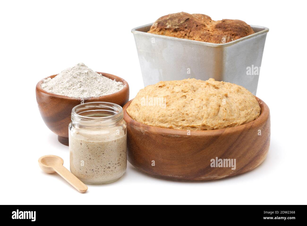 Lievito naturale per il pane in un vaso di vetro, ciotola di pasta di legno, ciotola di farina e pane appena sfornato in teglia bianca. Foto Stock