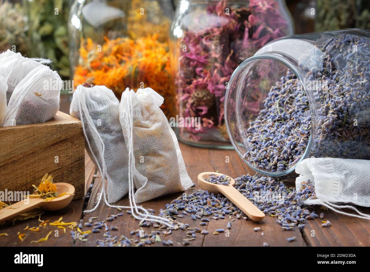 Sacchetti per il tè filtrati pieni di erbe medicinali. Vaso di vetro di fiori secchi di lavanda per la preparazione di tè alle erbe, vasi di varie erbe sane sullo sfondo. Alt Foto Stock