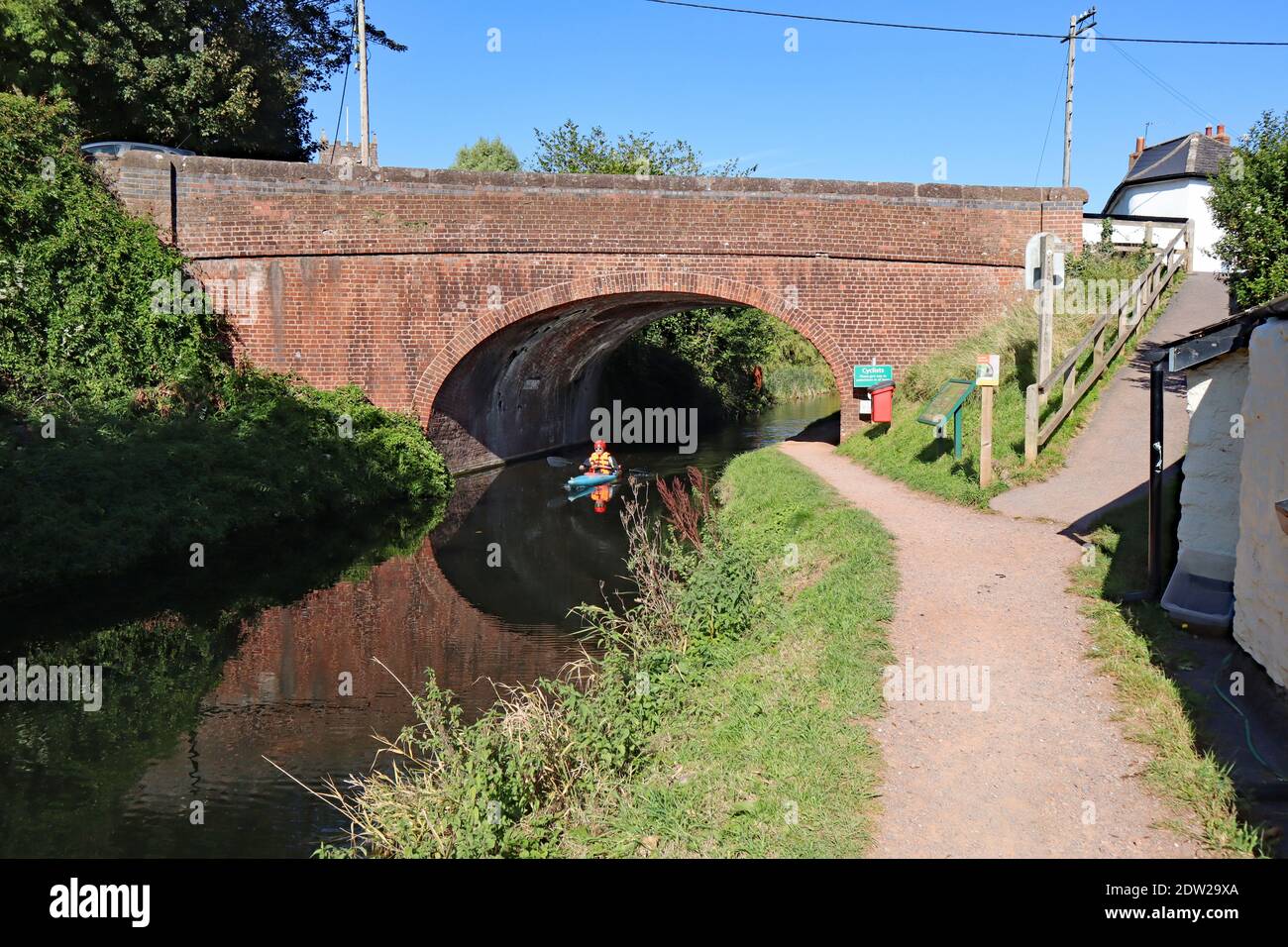 Un canoista pagaia sotto un ponte di canale a Sampford Peverell Sul canale Grand Western di Devon Foto Stock