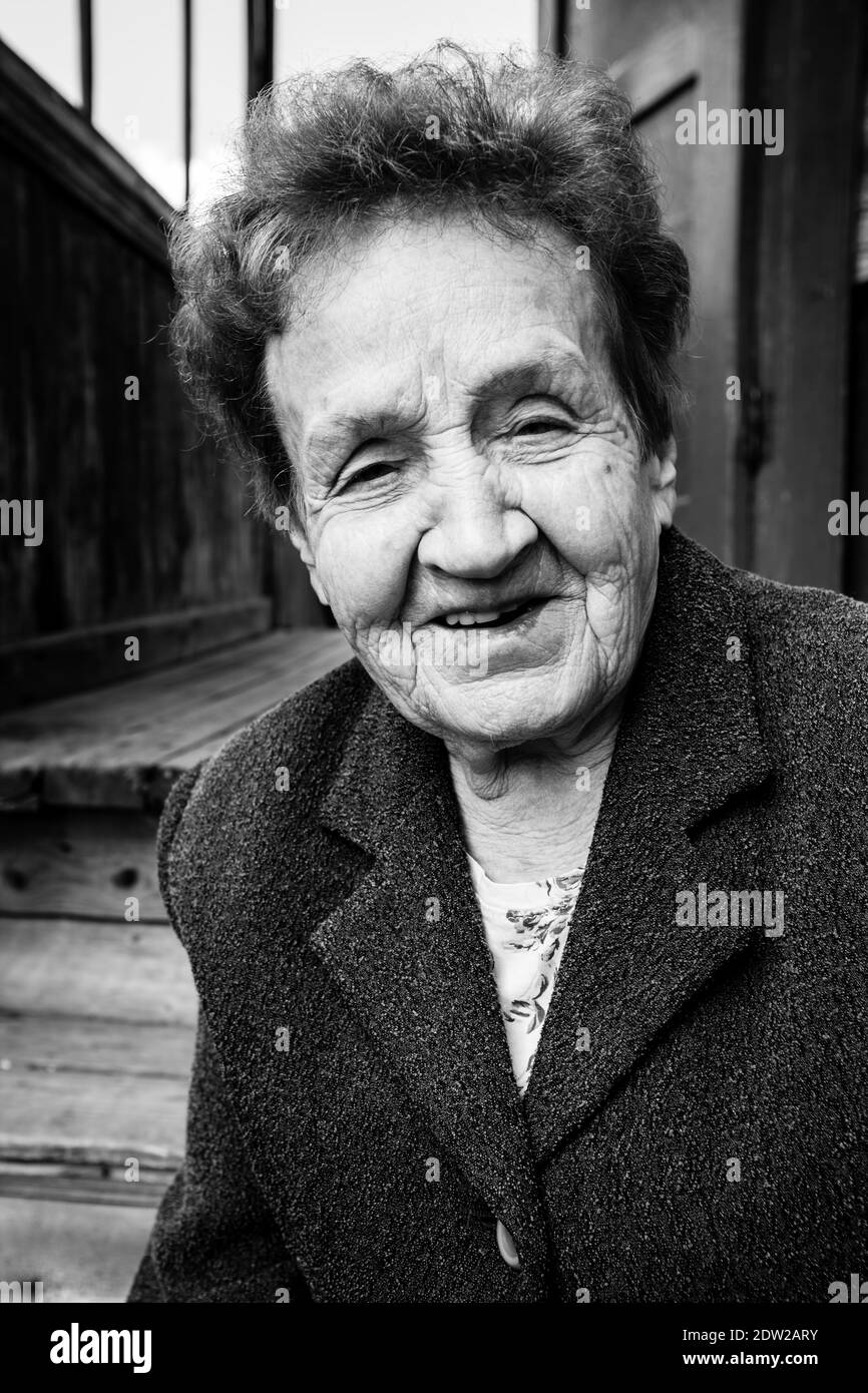 Ritratto di una vecchia donna vicino a una casa rurale. Foto in bianco e nero. Foto Stock