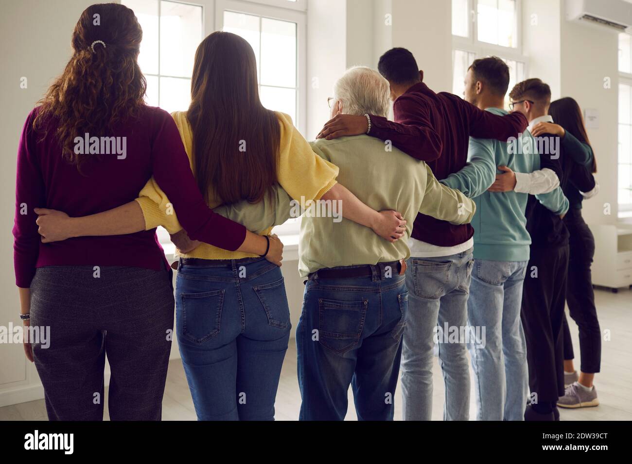 Gruppo di diversi membri della comunità che si abbracciano, sentendosi forti e uniti Foto Stock