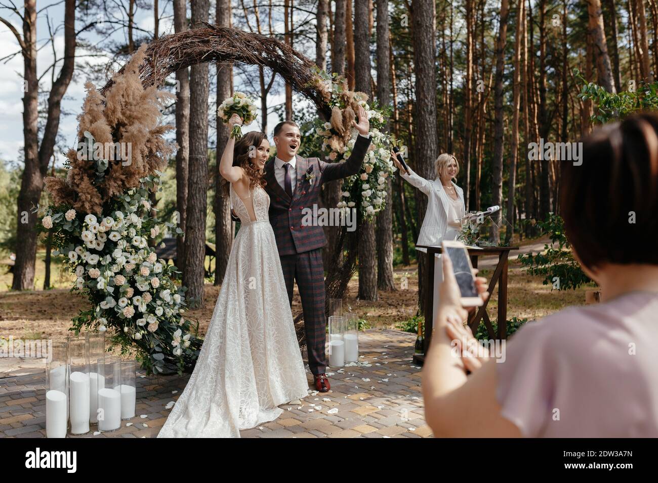 Felice sposa e sposo dopo aver detto sì l'uno all'altro di fronte all'arco di nozze. Sposi novelli alla cerimonia nuziale esterna Foto Stock