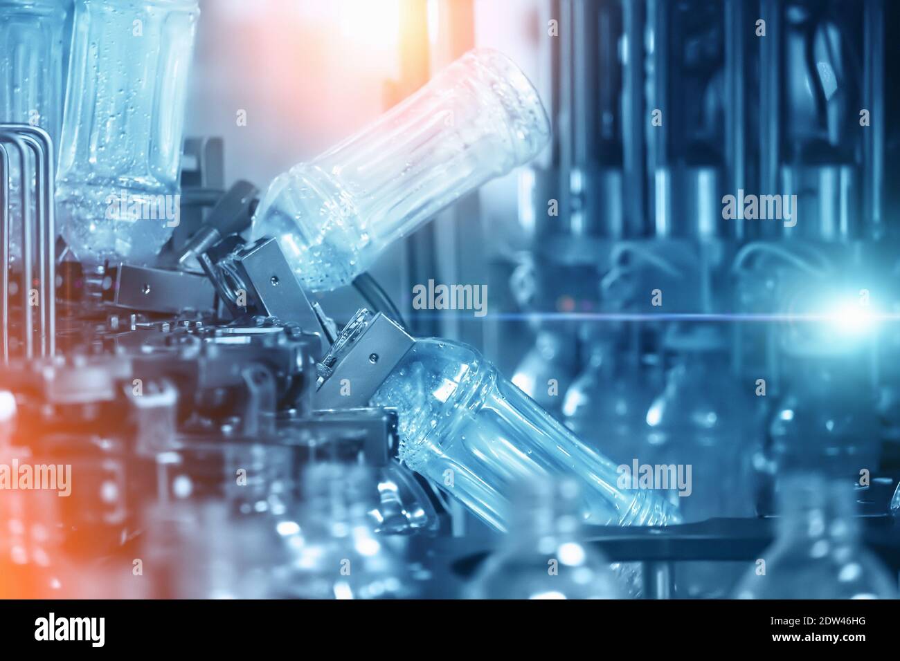 Fondo industriale astratto di colore blu con riempimento bottiglie in plastica all'interno della linea di trasporto di macchine industriali in impianti di imbottigliamento acqua. Foto Stock