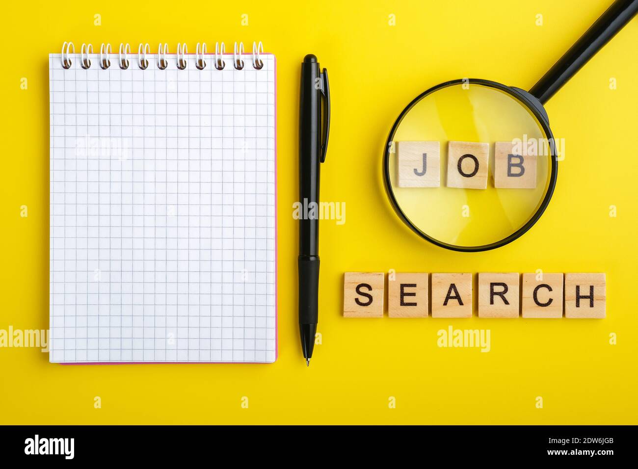 ricerca di lavoro con caratteri in legno, penna e blocco note vuoto su sfondo giallo Foto Stock
