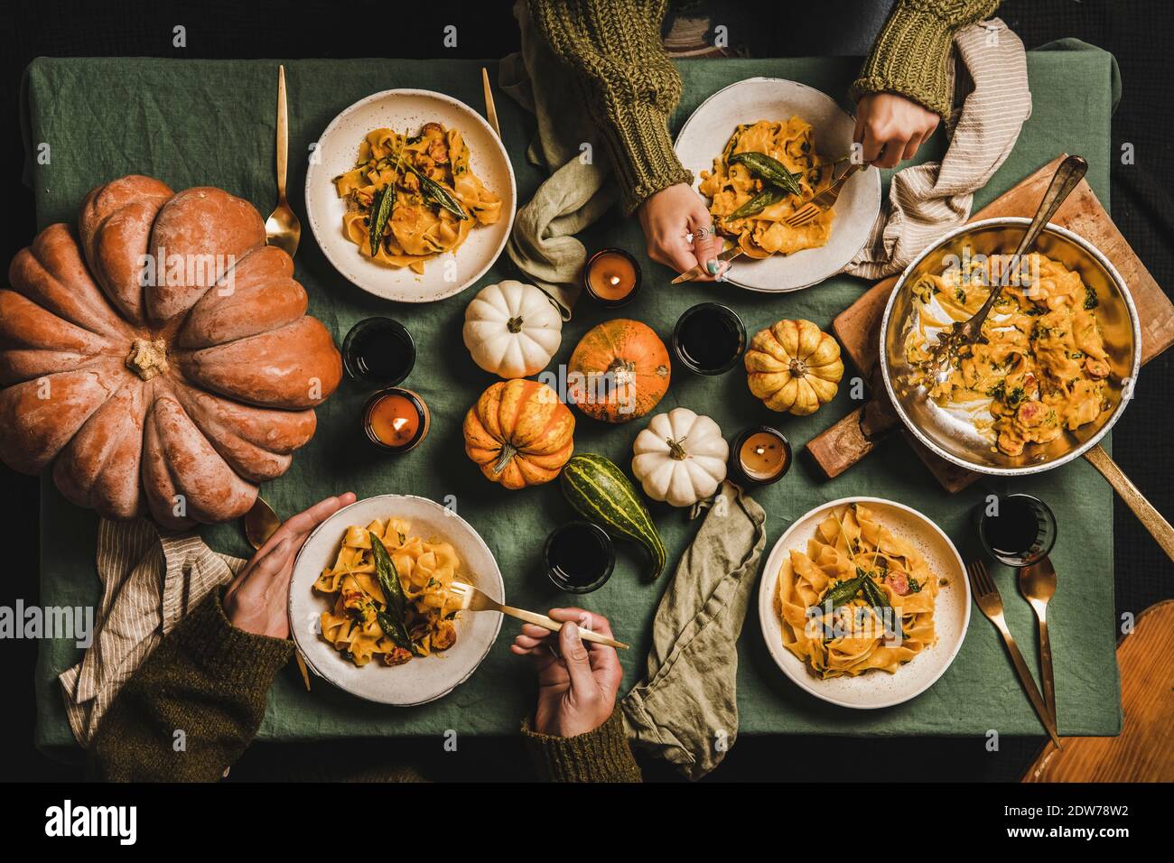 Piatto di cena d'autunno per la riunione, festa di festa del giorno del Ringraziamento. Persone amici mangiare pasta di zucca con salsiccia e salvia con r Foto Stock