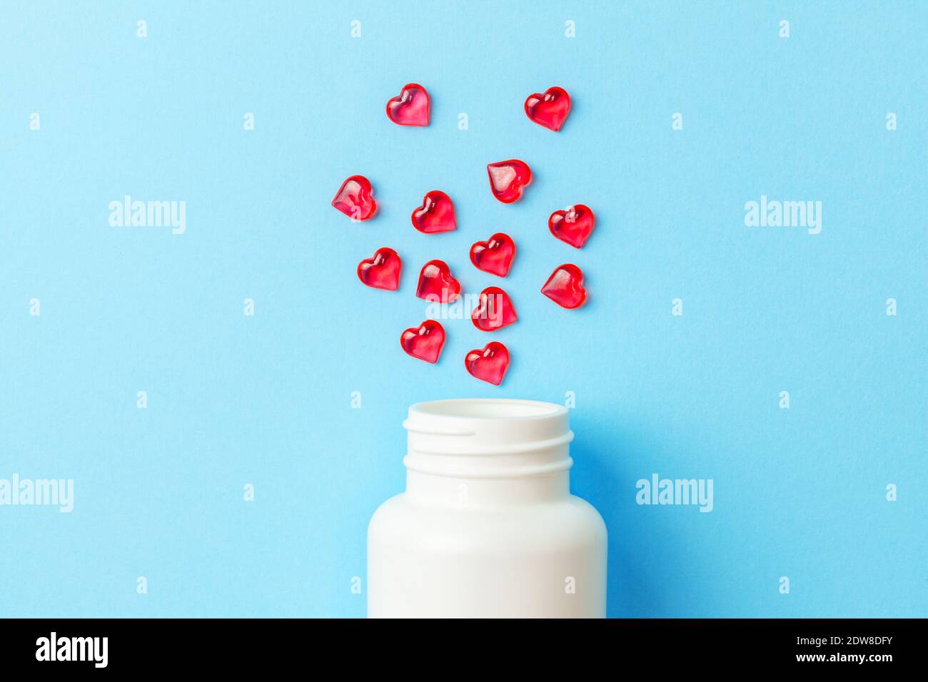 Pillole d'amore. Pillole rosse a forma di cuore con bottiglia su sfondo blu. Foto Stock
