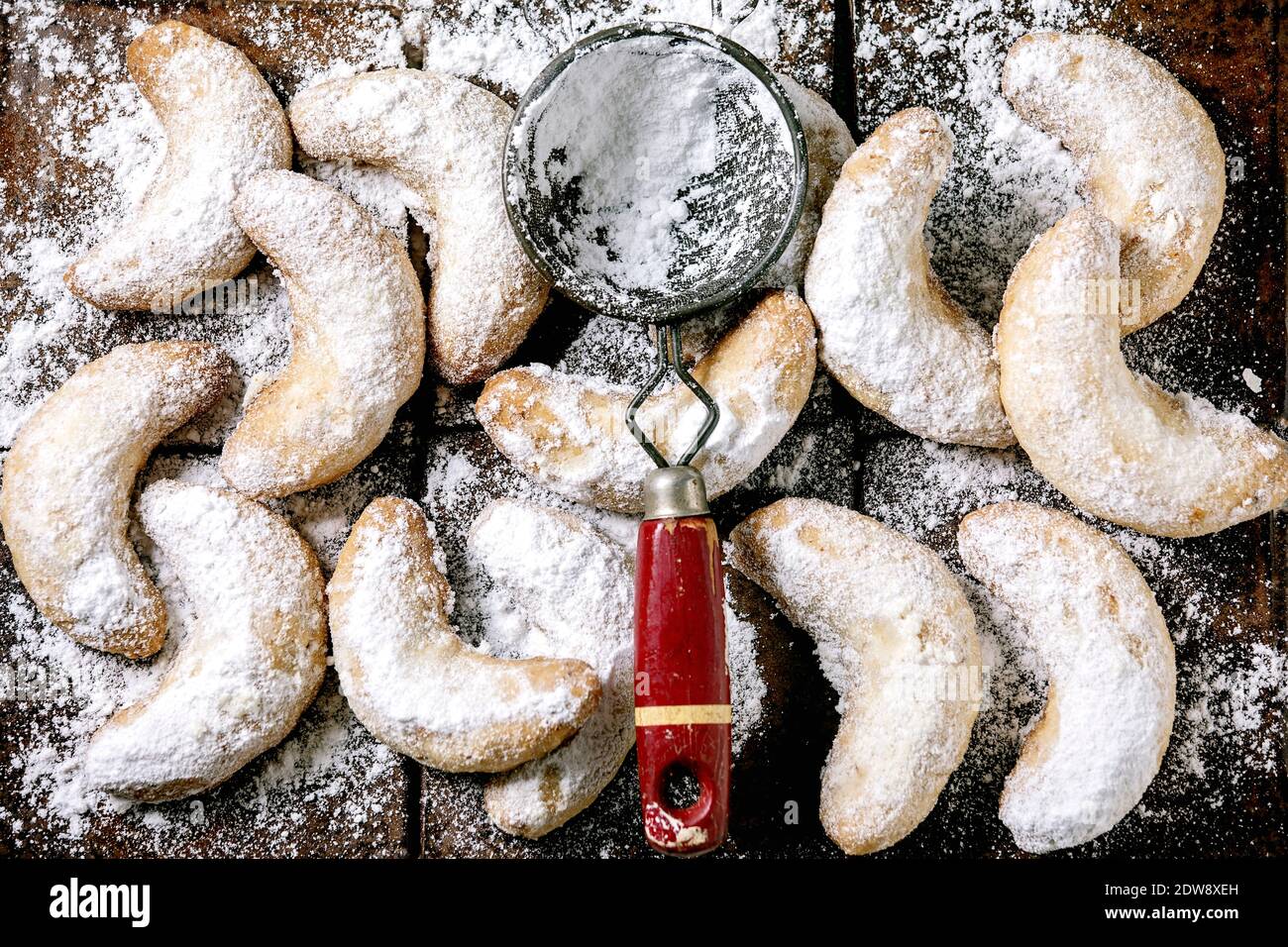 Biscotti shortcrosta di Natale tradizionali fatti in casa cressenti di vaniglia con zucchero a velo e setaccio vintage su sfondo di piastrelle di ceramica scuro. Vista dall'alto Foto Stock