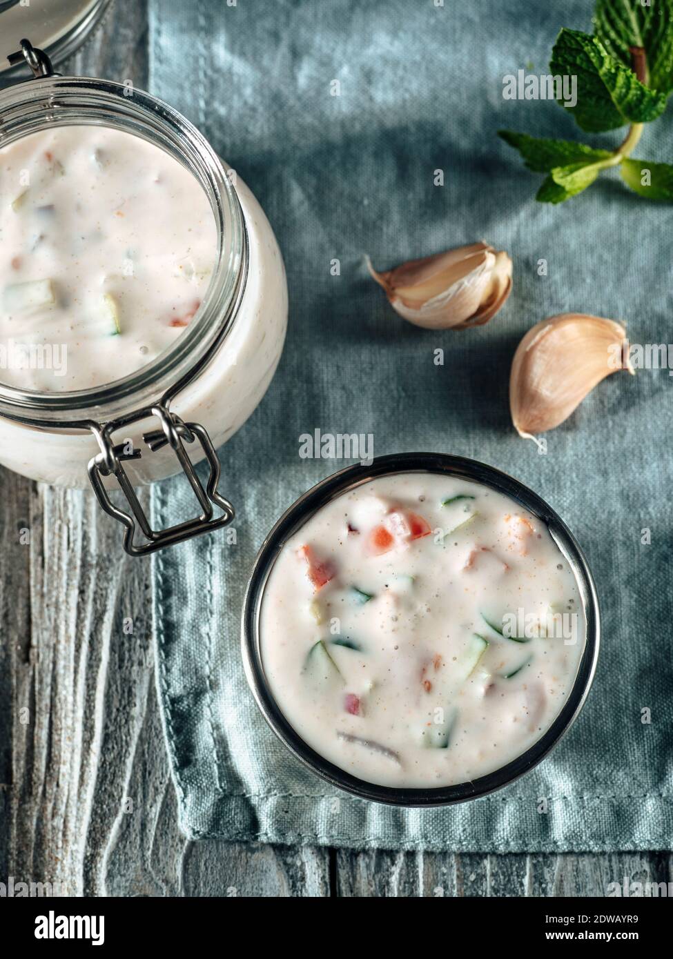 Autentica salsa raita di cetrioli pakistani su tovagliolo di lino blu su sfondo grigio di legno. Salsa di raita immergere con cetrioli, cipolla e pomodoro in sm Foto Stock