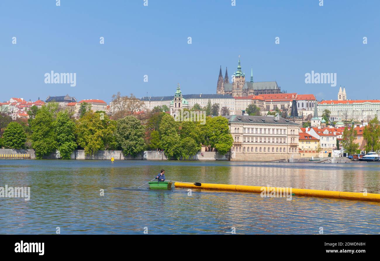 Praga, Repubblica Ceca - 30 aprile 2017: Vista della vecchia Praga durante il giorno d'estate. Fiume Moldava con un uomo su una piccola barca a fila verde Foto Stock