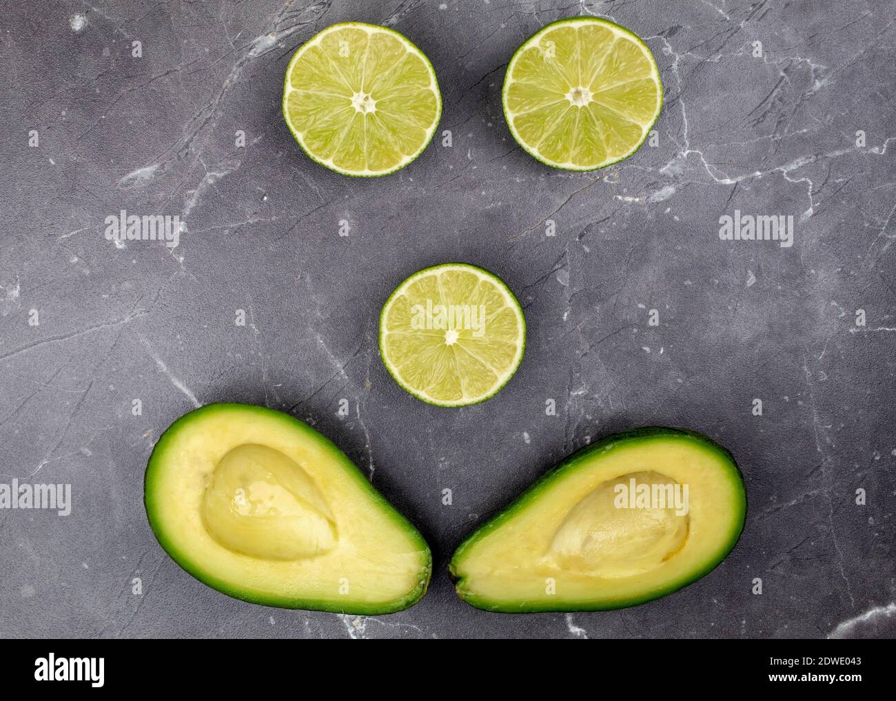 Emoticon di lime e avocado su sfondo grigio Foto Stock
