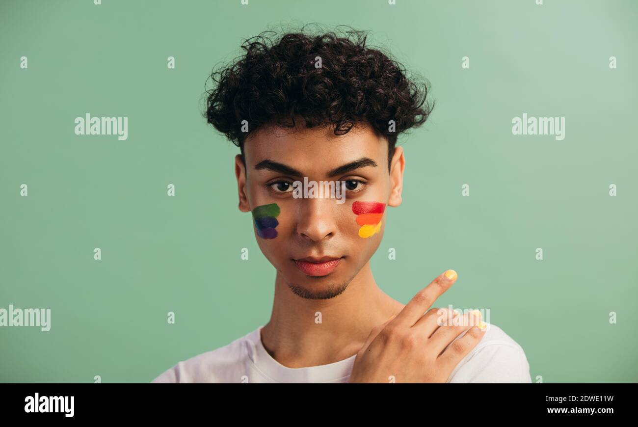 Ritratto di un giovane con bandiera LGBT dipinta sulle guance. Tema dell'uguaglianza e della libertà di scelta. Foto Stock