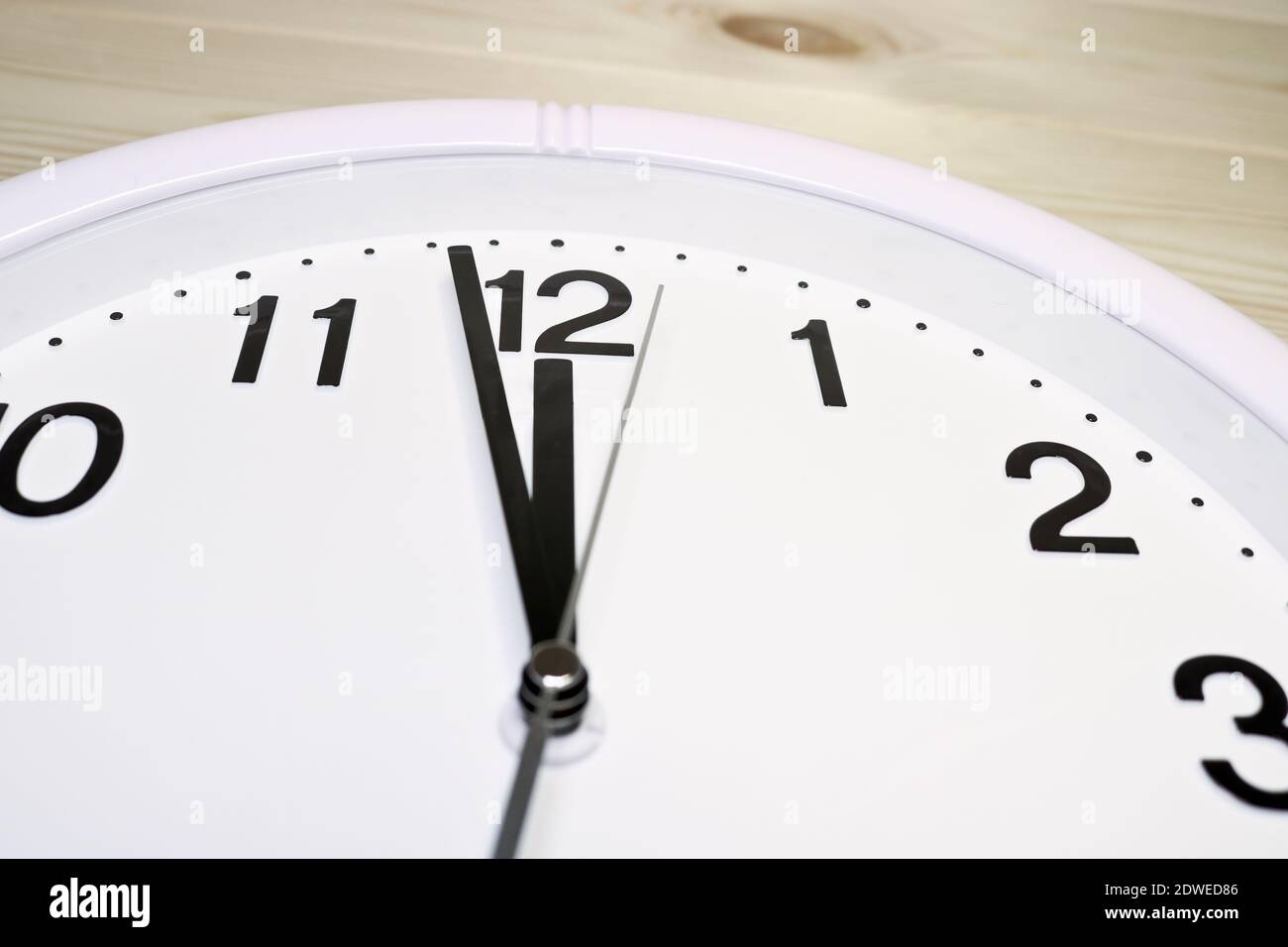 Quadrante di un orologio analogico primo piano su uno sfondo di legno.  L'ora è 23:59. Quadrante bianco, numeri neri Foto stock - Alamy