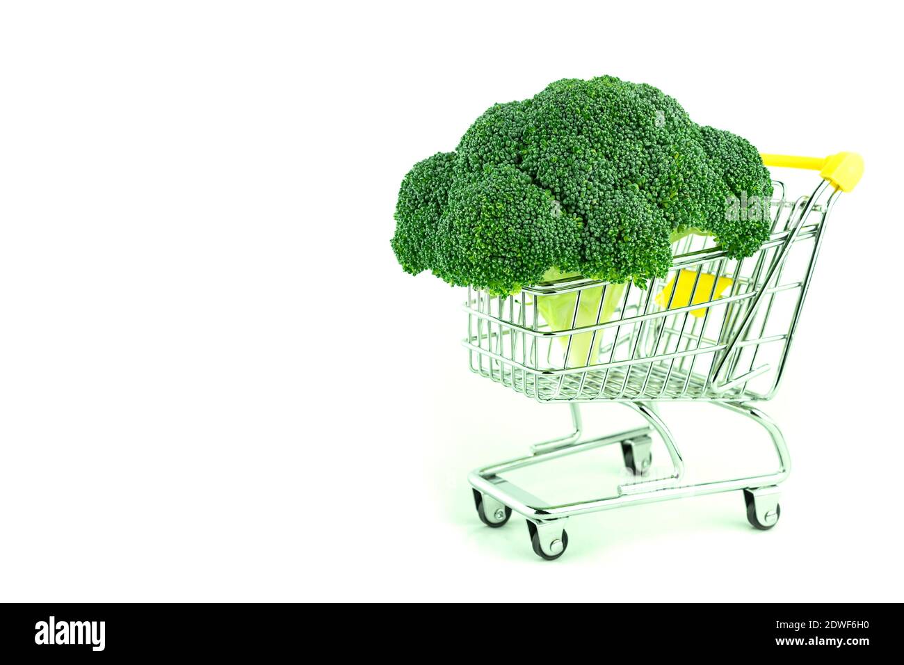 Cavolo di broccoli su sfondo bianco con spazio per il testo. Carrello per lo shopping in metallo e broccoli freschi. Inforescenza dei broccoli in un carrello piccolo su un whit Foto Stock
