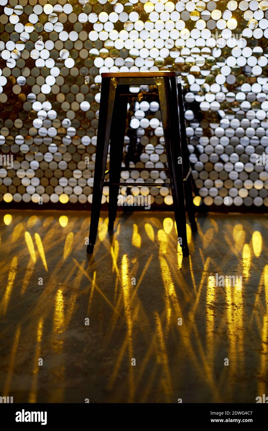 Sgabello alto su una base di metallo contro lo sfondo della parete con  paillettes. Il riflesso si riflette sul pavimento. Design glamour Foto  stock - Alamy