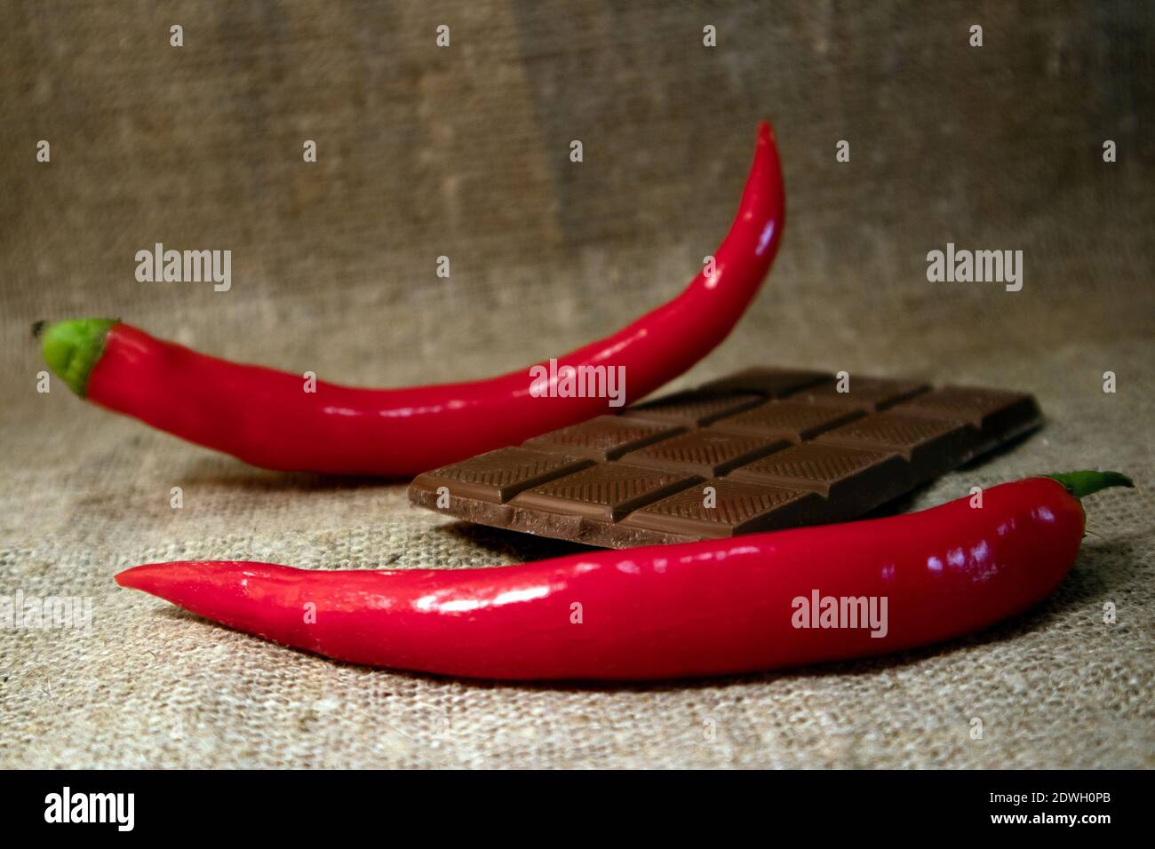 Peperoncino rosso caldo e barretta di cioccolato rotta contro ruvida burlap Foto Stock