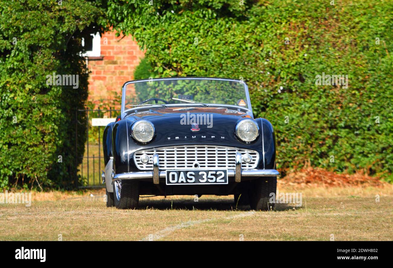 Nero classico trionfo TR3 una vettura parcheggiata sul verde del villaggio. Foto Stock