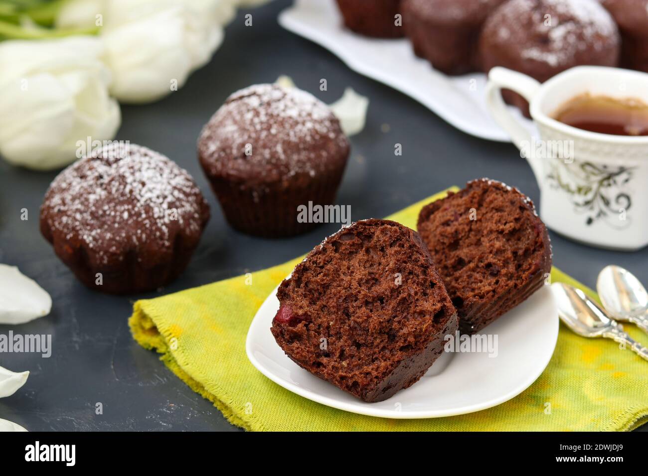 Muffin al cioccolato con ciliegia, ricoperti di zucchero in polvere su sfondo scuro Foto Stock