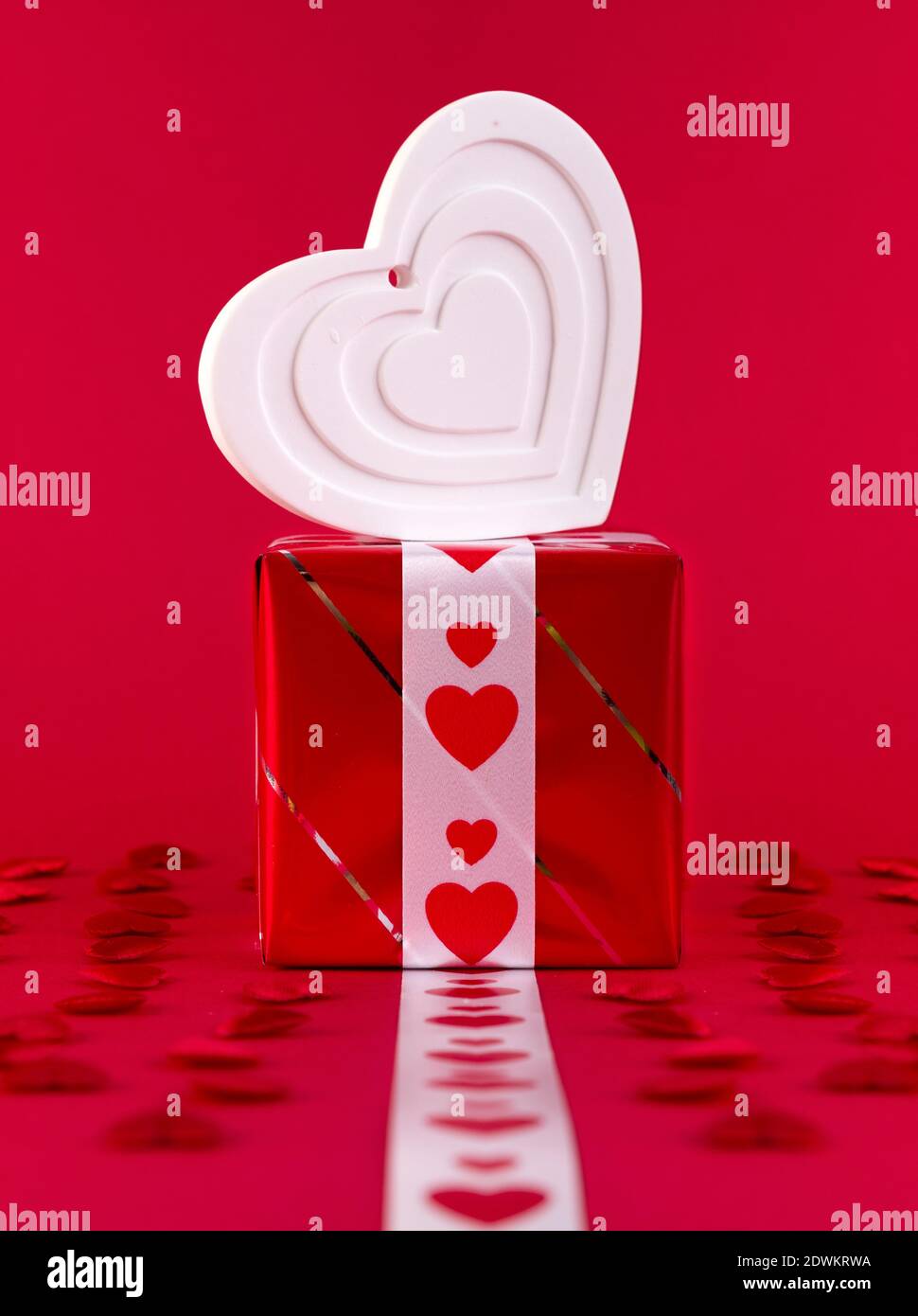 Forma bianco cuore su confezione regalo su sfondo rosso Foto Stock