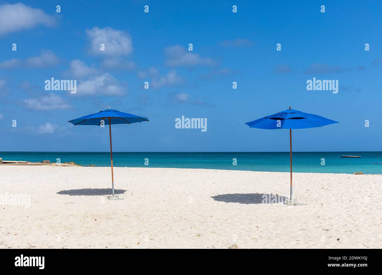 Due ombrelloni blu (ombrelloni) su una spiaggia di sabbia bianca caraibica con mare turchese e cielo blu. Palm Beach Aruba, isola caraibica Foto Stock