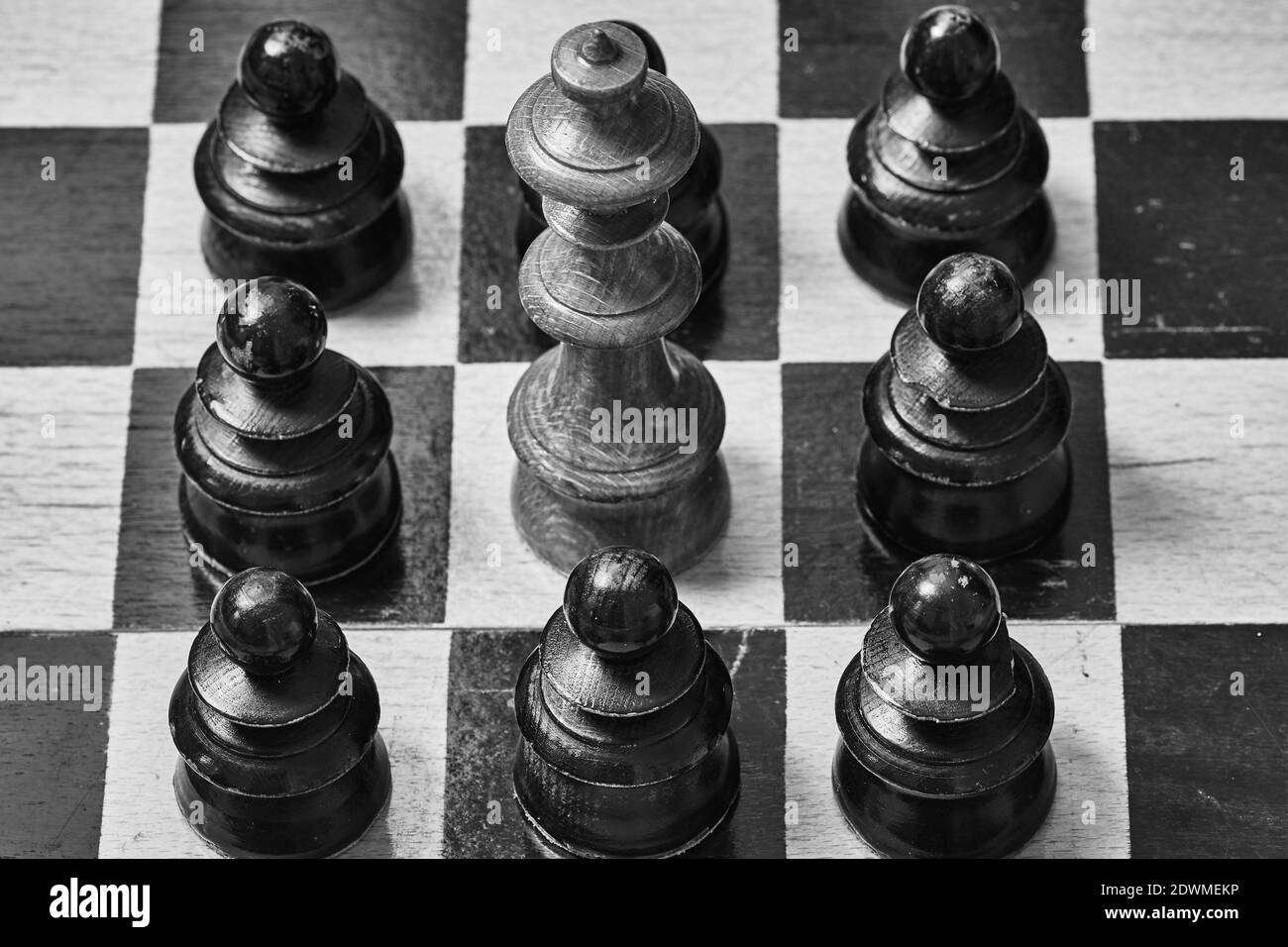 Closeup del pezzo di scacchi del re circondato da pedine nere Foto Stock
