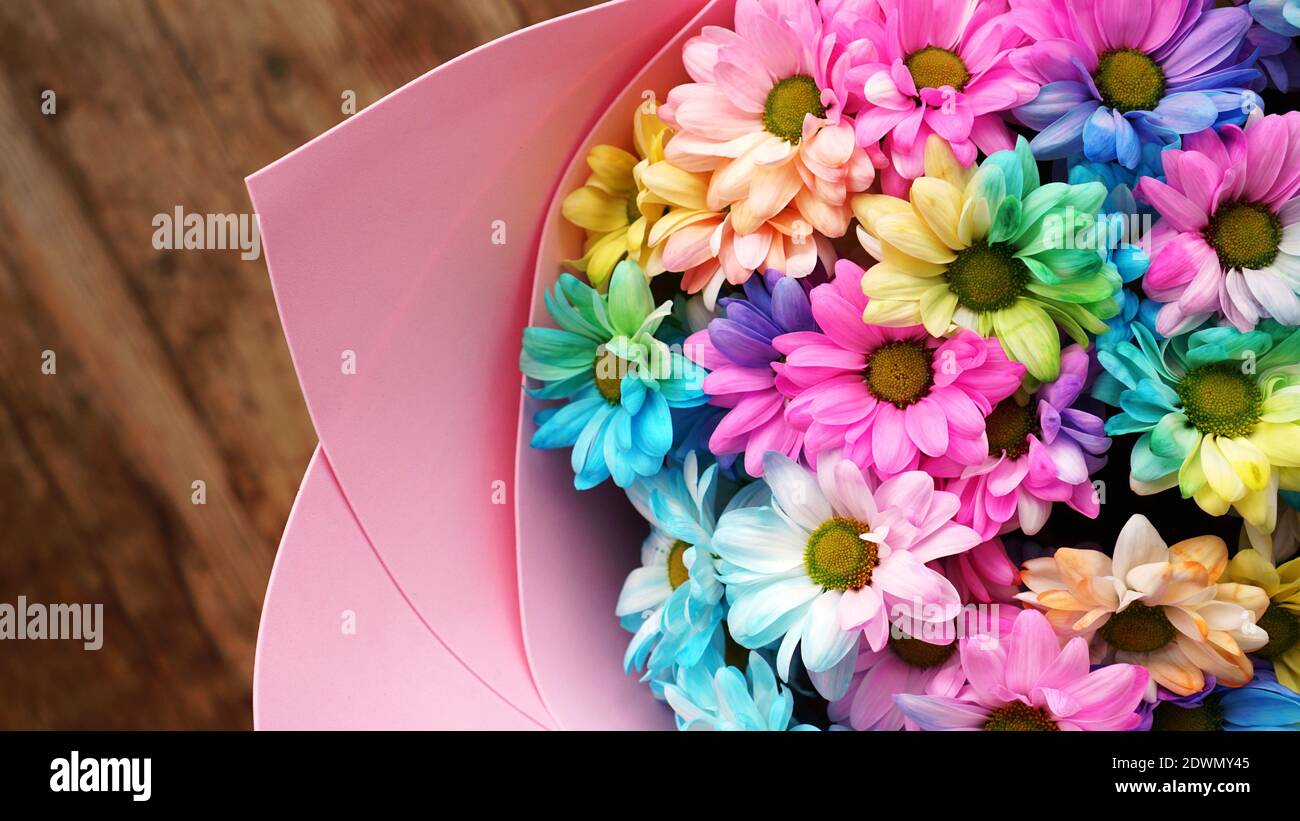 Primo piano fiori fiori arcobaleno fiori bouquet luminoso su sfondo di legno Foto Stock